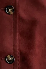 Chaqueta de tejido suave con acabado efecto gamuza, cuello camisero, cierre frontal con botones y bolsillos delanteros insertados.