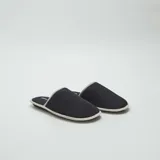 Pantuflas mules negras con borde gris.