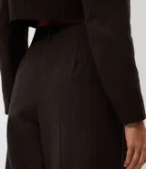 Pantalón sastre marrón de corte amplio y recto, con pinzas frontales y cintura estructurada.