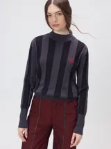 Sweater de punto con diseño de rayas verticales en tonos negro y gris oscuro. Presenta cuello alto tipo polera, mangas largas con puños ajustados y ruedo elástico. Incluye un pequeño bordado en color rojo en el pecho.