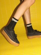 Championes de lona negra con plataforma y puntera de goma marrón, cordones negros y costuras en contraste.