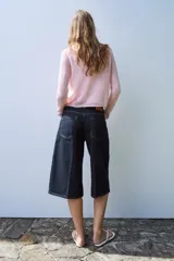 Chaqueta de punto color rosado con cuello polo, manga larga y cierre frontal con botones.