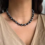 Collar corto de cuentas de vidrio negras con lunares blancos.