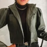 Campera corta verde militar de cuero sintético, con cuello clásico, mangas abullonadas y bolsillos frontales con solapa.
