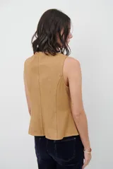 Chaleco de gamuza color caramelo, con cierre frontal de botones y bolsillos laterales simulados.