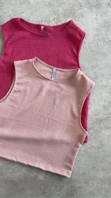 Musculosa corta de tejido de punto color rosa pálido con textura acanalada horizontal.