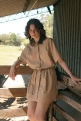 Vestido corto verde militar de microfibra con cuello camisero negro, cintura elastizada con cordón de ajuste y mangas cortas con dobladillo. Cierre frontal con botones.