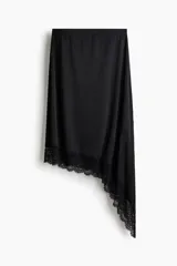 Pollera midi de punto color negro, con cintura elástica y bajo asimétrico decorado con un ribete de encaje.