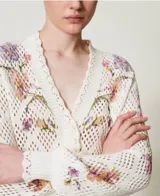 Cárdigan de punto calado color crema con estampa floral en tonos rosa y lila, escote en V y cierre frontal con botones.