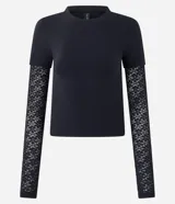 Blusa tipo baby look color negro, con cuerpo de algodón y mangas largas integradas de encaje con diseño floral. Presenta un diseño de superposición que simula una manga corta sobre la manga larga de encaje.