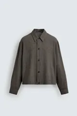 Sobrecamisa de corte cropped confeccionada en tejido ligero con algodón, con estampado de cuadros pequeños en tonos oscuros. Presenta cuello solapa, cierre frontal de botones, manga larga con puño abotonado y bajo con elástico en la espalda.
