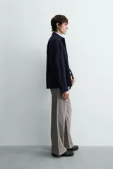 Pantalón relaxed fit color marrón con patrón de espiga, confeccionado en tejido con viscosa. Presenta pliegues frontales, bolsillos laterales y bolsillos traseros de vivo. Cierre frontal con cremallera y botón.