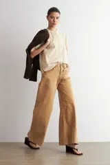 Camisa de manga corta color beige con sutiles rayas verticales blancas, cuello mao y cierre frontal oculto con botones.