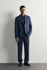 Pantalón de traje de corte regular fit en color azul marino, confeccionado en una mezcla de lino y lana. Cuenta con bolsillos delanteros, bolsillos traseros de doble vivo con botón y raya marcada en el centro de las piernas.