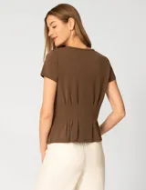 Remera blanca de manga corta con cuello redondo, confeccionada en una mezcla de modal, poliéster y elastano. Presenta un diseño con alforzas verticales en el frente que aportan estructura y una silueta relajada.