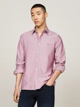 Camisa de corte slim confeccionada en algodón Oxford con textura dobby. Presenta cuello con botones, puños redondeados y el logo de Tommy Hilfiger bordado en el pecho.