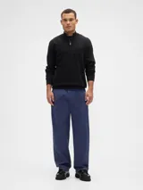 Buzo de tejido de punto color negro, con cuello alto y cierre frontal parcial. Presenta puños y ruedo acanalados.