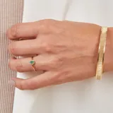 Esclava rígida de oro 18k con acabado satinado y diseño de cinta plana. Presenta una textura fina en su superficie y un diseño minimalista.