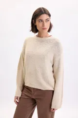 Sweater de punto de cinta en color crudo, de manga larga, con cuello redondo y diseño holgado.