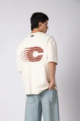 Remerón de corte oversized confeccionado en tejido rústico, con cuello redondo y mangas cortas. Presenta un diseño minimalista con una pequeña estampa frontal centrada en el pecho.