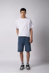 Bermuda de jean color negro lavado, de corte regular y largo a la rodilla, con dobladillo doblado en el ruedo.