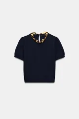Top de punto azul marino de manga corta abullonada, con cuello redondo decorado con aplicación de bolas doradas y cierre en la espalda con abertura y botón oculto.