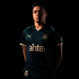 Camiseta de fútbol Puma del Club Atlético Peñarol, modelo Third Jersey 2026. Diseño en tonos oscuros con patrón de ondas en relieve, detalles en color dorado en cuello, mangas y logos. Incluye escudo del club, logo de Puma y sponsor Antel en el frente.