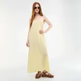 Vestido largo fluido de color amarillo pastel, con tirantes finos, escote en V y tajo lateral.