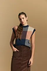 Chaleco tejido de punto con diseño de bloques a cuadros en tonos rosados, marrones y beige. Presenta cuello redondo y terminaciones acanaladas en cuello y sisas.