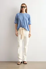 Camisa de manga corta a rayas azules y blancas, con cuello mao y cierre frontal oculto.