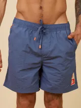 Short de baño tipo volley color azul marino, con cintura elástica y cordón ajustable con punteras naranjas. Presenta un parche con logo de la marca en la parte inferior de la pierna izquierda.