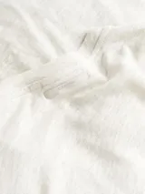 Remera de lino color gris claro, con cuello redondo y mangas cortas.