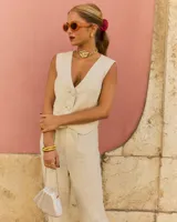 Chaleco color crudo con escote en pico y cierre frontal con botones forrados a tono.