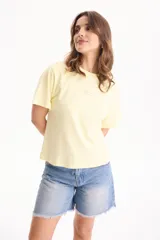 Remera de algodón amarilla de manga corta, con corte suelto y pequeño aplique rectangular en el pecho.