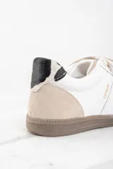 Zapatillas deportivas de cuero blanco con puntera y talón en gamuza color beige. Detalle de pelo animal print en el talón y suela de goma color caramelo.