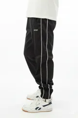 Pantalón de jogging negro con vivo lateral doble blanco, corte holgado, tiro medio, botamanga elastizada y cierres en los tobillos.