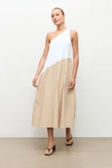 Maxi vestido largo de corte evasé, diseño bicolor con parte superior blanca y parte inferior beige, escote asimétrico de un solo hombro.