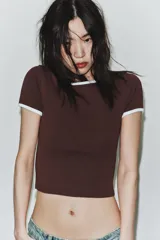 Camiseta negra de manga corta y cuello redondo, con vivos a contraste en el cuello y las mangas.