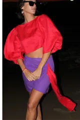 Falda violeta de lino, corte mini con diseño cruzado y lazo lateral rojo.