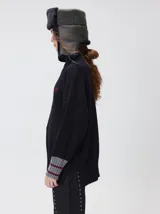 Pullover de punto color rojo, con cuello tortuga, corte holgado y mangas largas con puños acanalados en contraste con rayas blancas. Presenta un logo bordado en el pecho.