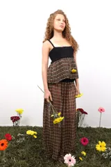 Top de diseño artesanal con cuerpo superior tejido en crochet negro y parte inferior de corte peplum en tejido plano de telar con trama a cuadros en tonos oscuros, rojo y amarillo.