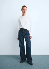 Jeans tiro alto wide leg de color azul, con diseño de cinco bolsillos, presillas para cinturón y cierre frontal con cremallera y botón.