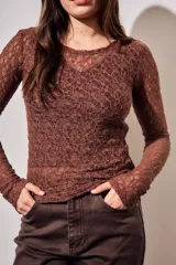 Remera de encaje negro ajustada al cuerpo, de manga larga y diseño transparente.
