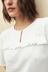 Blusa negra con textura, canesú con encaje, volados, corte fluido y mangas cortas amplias.