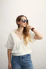 Blusa blanca con diseño cruzado, escote en V y mangas cortas.