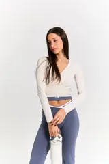 Top de manga larga color crudo, con diseño cruzado en el frente y escote en V, confeccionado en tejido elástico ajustado.