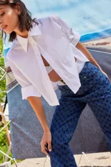 Jean de tiro bajo y corte oversize, confeccionado en denim azul con monograma grabado a láser en toda la prenda. Presenta doble botón metálico en la cintura y diseño de cinco bolsillos.
