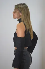 Blusa corta negra con cuello alto, hombros descubiertos y mangas largas.