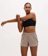 Bermuda deportiva modelo runner color beige, con cintura elástica, bajo redondeado y aberturas laterales. Incluye un pequeño bolsillo funcional en la parte trasera.