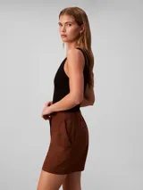 Short cargo de talle alto confeccionado en una mezcla de lino y algodón. Presenta cierre frontal con botón y cremallera, bolsillos laterales con solapa y botones decorativos, ofreciendo un estilo utilitario y relajado.